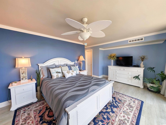 bedroom with baseboards, visible vents, ornamental molding, and light wood finished floors