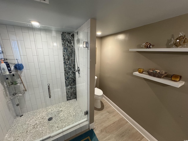 bathroom featuring baseboards, a stall shower, toilet, and wood finished floors