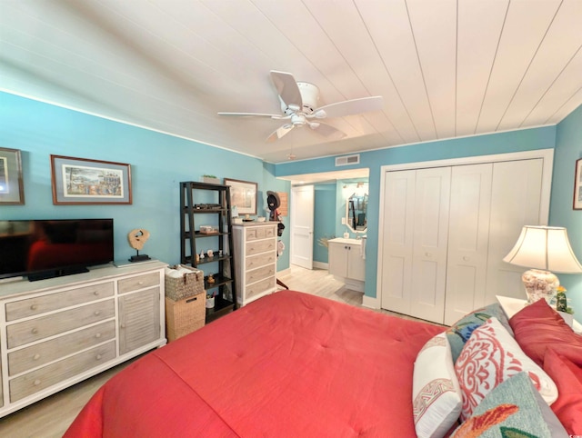 bedroom with connected bathroom, a ceiling fan, wood finished floors, visible vents, and a closet