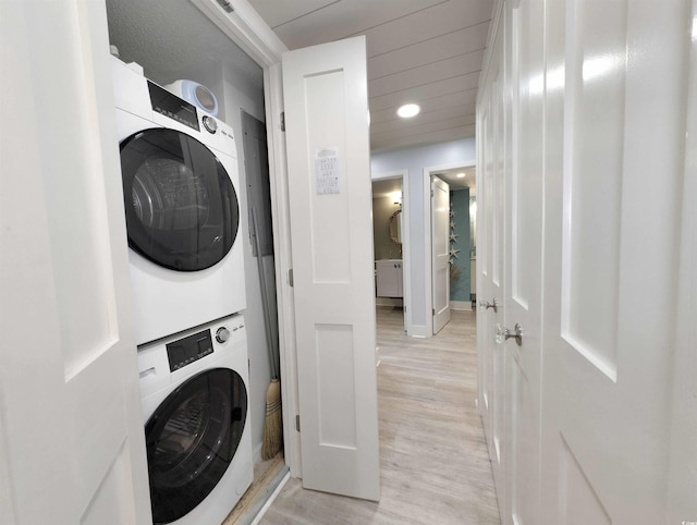 clothes washing area featuring laundry area, light wood finished floors, recessed lighting, baseboards, and stacked washer and clothes dryer