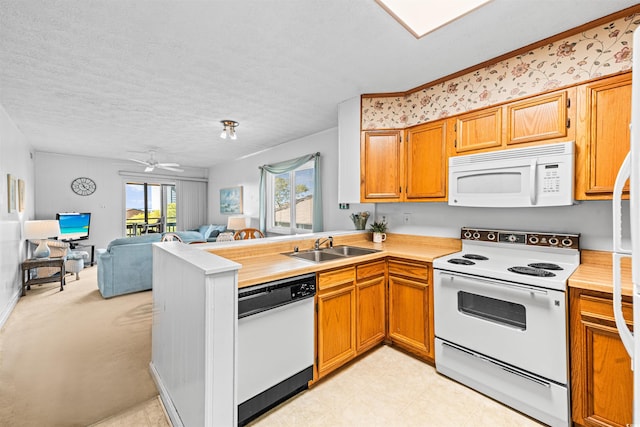 kitchen featuring a peninsula, white appliances, open floor plan, light countertops, and a sink