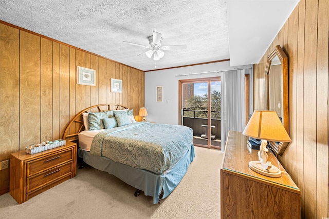carpeted bedroom with ceiling fan, ornamental molding, wood walls, and access to exterior