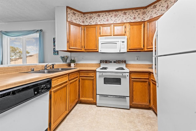 kitchen with brown cabinetry, crown molding, white appliances, light countertops, and a sink