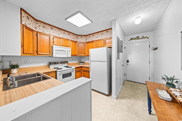 kitchen featuring a peninsula, white appliances, light countertops, brown cabinets, and a sink