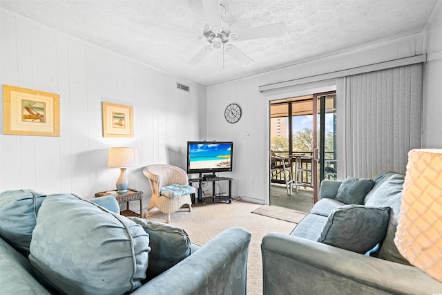living area with carpet flooring, a textured ceiling, ceiling fan, and visible vents