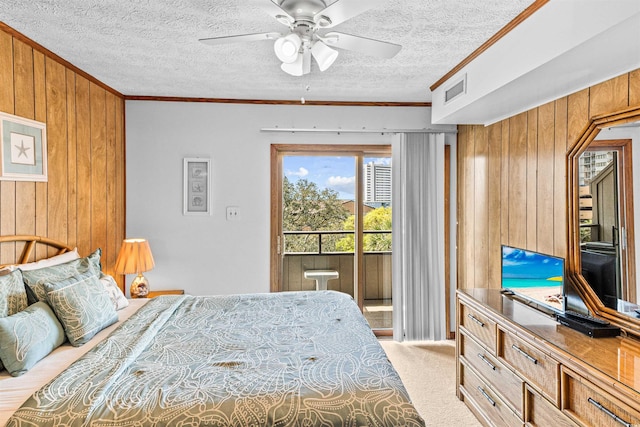 carpeted bedroom with a textured ceiling, ornamental molding, wood walls, and access to outside