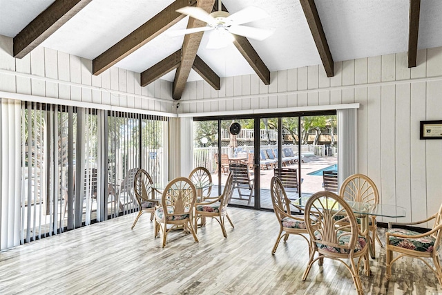 sunroom / solarium featuring a healthy amount of sunlight, beam ceiling, and wood finished floors