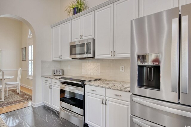 78 Saltwind Loop, Murrells Inlet, SC 29576 - kitchen with arched walkways, stainless steel appliances, white cabinetry, baseboards, and backsplash