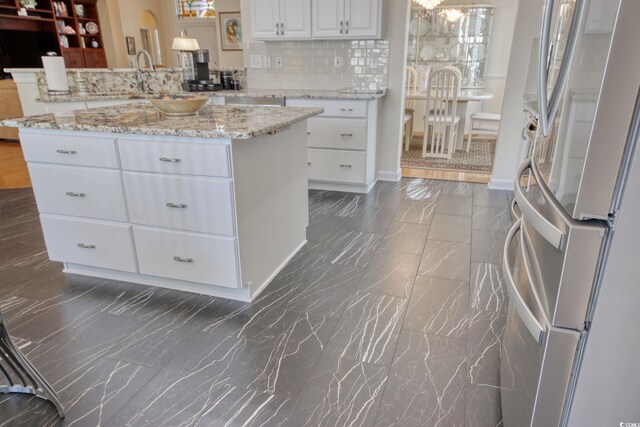 78 Saltwind Loop, Murrells Inlet, SC 29576 - kitchen with freestanding refrigerator, marble finish floor, decorative backsplash, white cabinetry, and arched walkways