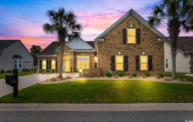 view of front of house featuring brick siding and a lawn