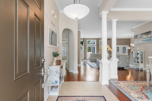 entryway with crown molding, decorative columns, and wood finished floors