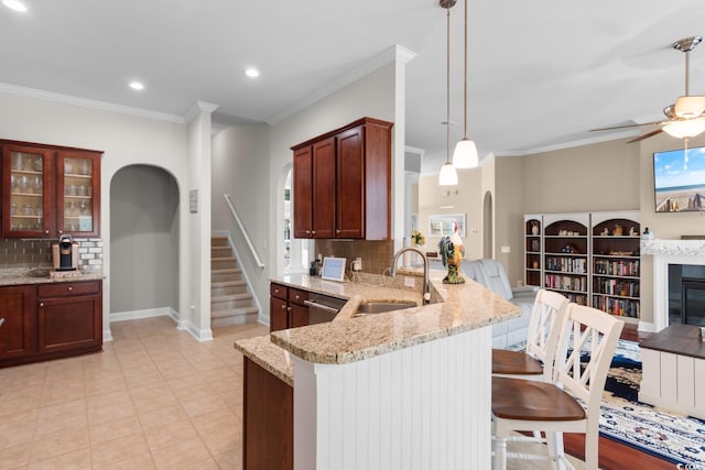 kitchen featuring decorative backsplash, a sink, a peninsula, a kitchen bar, and a ceiling fan