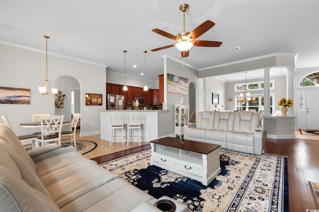 living area featuring arched walkways, ornamental molding, hardwood / wood-style flooring, and ceiling fan with notable chandelier