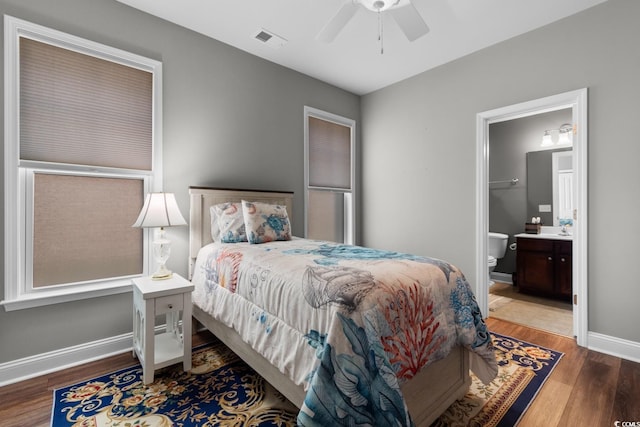 bedroom featuring visible vents, connected bathroom, baseboards, and wood finished floors