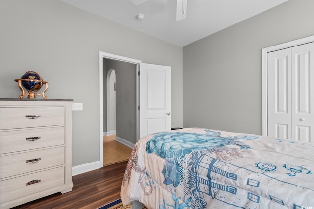 bedroom featuring ceiling fan, arched walkways, baseboards, a closet, and dark wood-type flooring