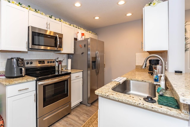 kitchen featuring appliances with stainless steel finishes, a sink, recessed lighting, white cabinetry, and backsplash