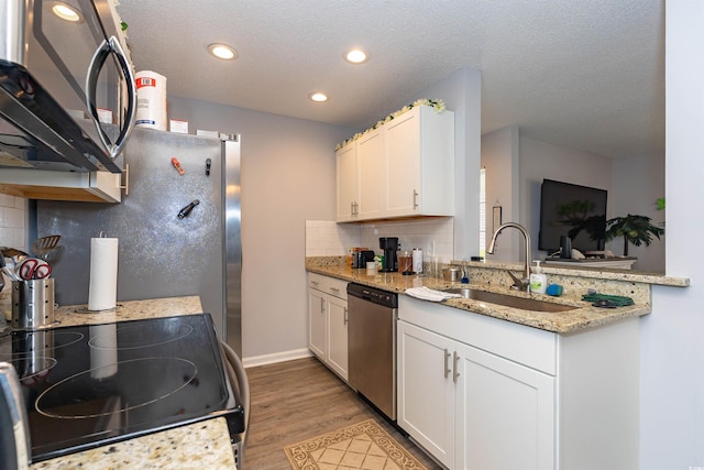 kitchen with decorative backsplash, appliances with stainless steel finishes, light wood-type flooring, a sink, and recessed lighting