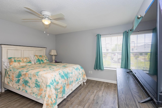bedroom featuring baseboards, ceiling fan, a textured ceiling, and wood finished floors