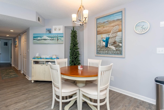 dining space with visible vents, wood finished floors, baseboards, a textured ceiling, and a chandelier