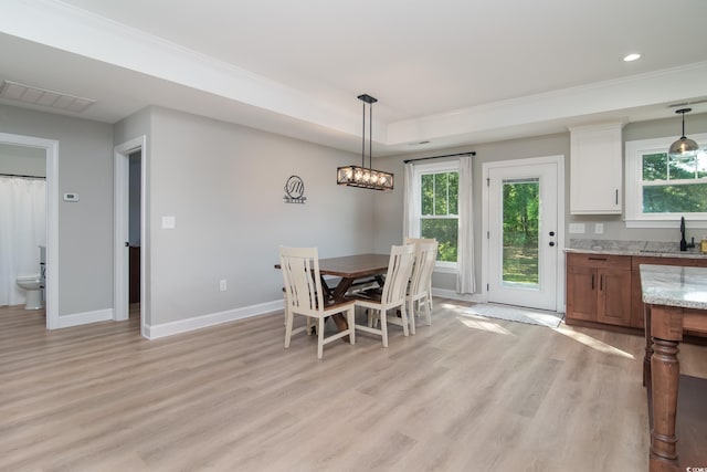 dining space with visible vents, light wood-style flooring, baseboards, and a tray ceiling