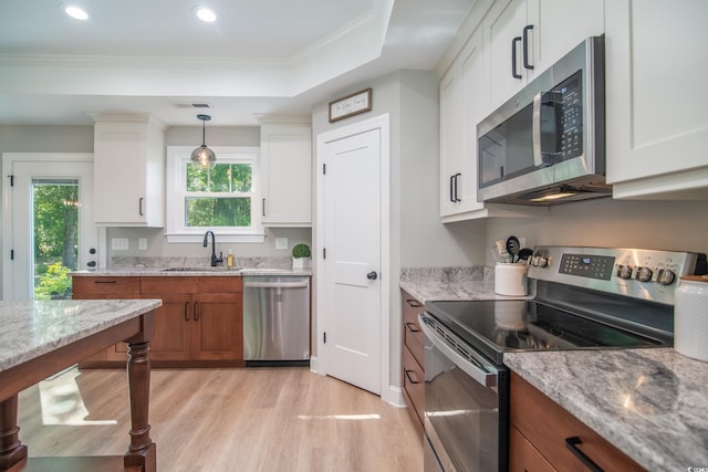 kitchen with visible vents, appliances with stainless steel finishes, a sink, white cabinets, and light wood-style flooring
