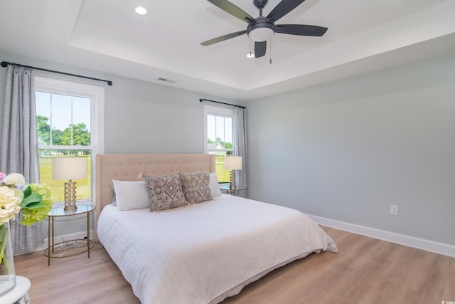 bedroom featuring recessed lighting, baseboards, light wood-style flooring, and a raised ceiling