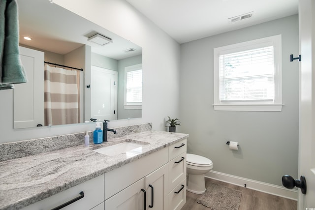 bathroom featuring baseboards, wood finished floors, visible vents, and vanity