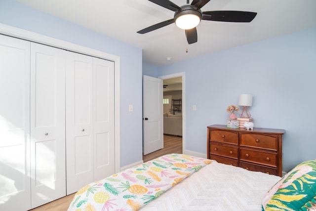 bedroom featuring a ceiling fan, baseboards, light wood finished floors, and a closet