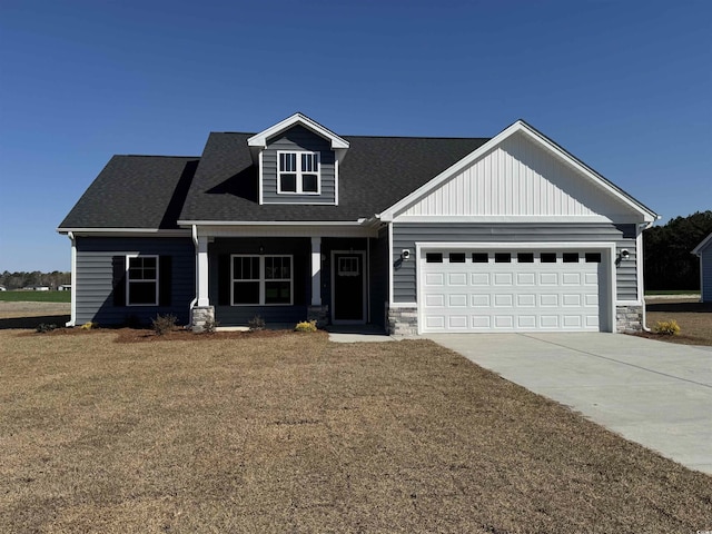 craftsman-style home with a porch, an attached garage, driveway, and stone siding
