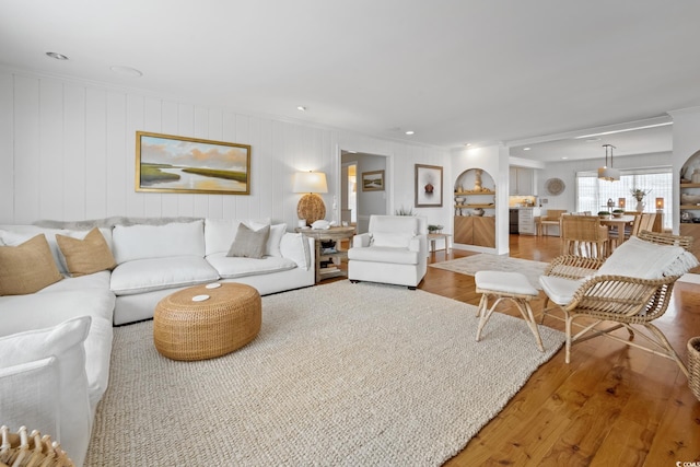 living area with ornamental molding and wood finished floors