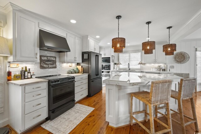 109 Pioneer Loop, Georgetown, SC 29440 - kitchen featuring wall chimney range hood, black appliances, backsplash, white cabinets, and recessed lighting