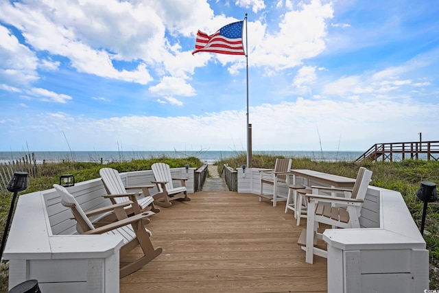 wooden deck featuring a beach view and a water view