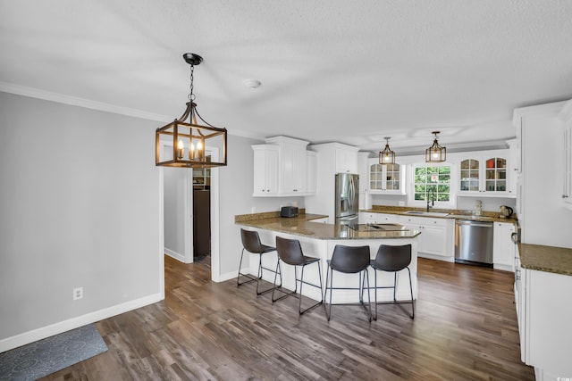 kitchen featuring white cabinets, a sink, stainless steel appliances, a peninsula, and glass insert cabinets