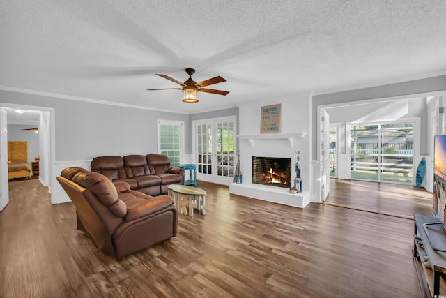 living area with a ceiling fan, a textured ceiling, and a fireplace