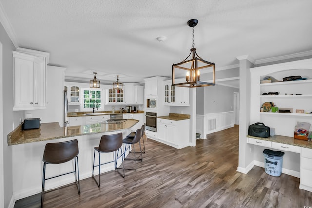 kitchen featuring a sink, white cabinetry, appliances with stainless steel finishes, and a peninsula