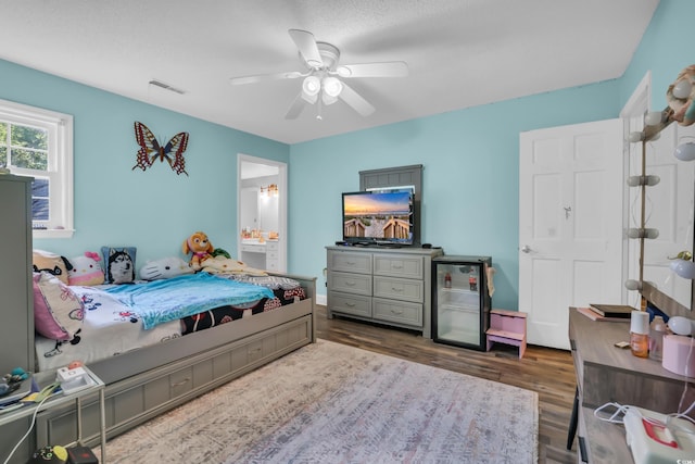 bedroom featuring a ceiling fan, visible vents, wood finished floors, and ensuite bath