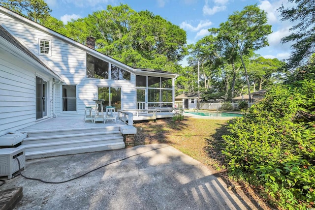 view of yard featuring a storage unit, a sunroom, a deck, a fenced in pool, and a patio