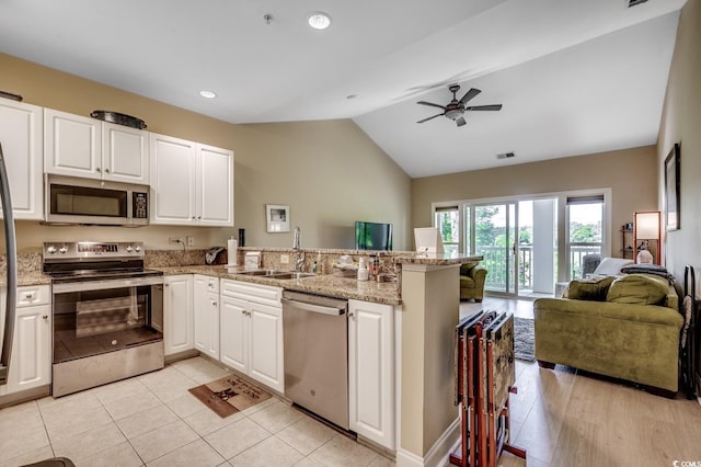 kitchen featuring a sink, stainless steel appliances, open floor plan, a peninsula, and lofted ceiling