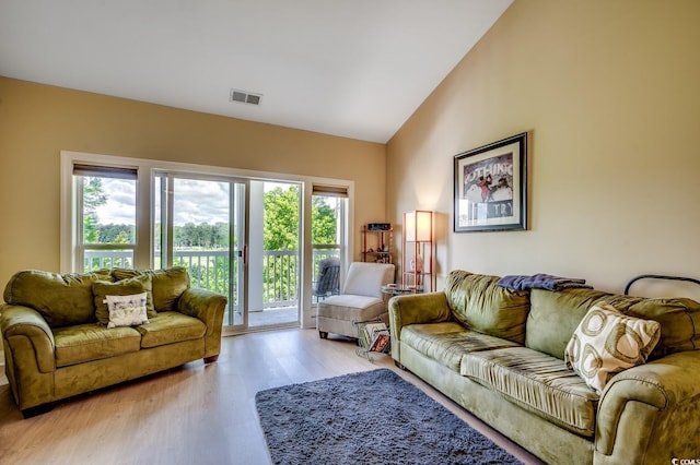 living area featuring high vaulted ceiling, visible vents, and wood finished floors