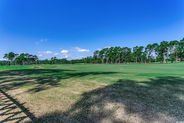 surrounding community with golf course view and a yard