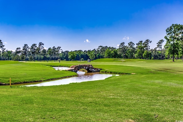 view of community featuring a water view, view of golf course, and a yard