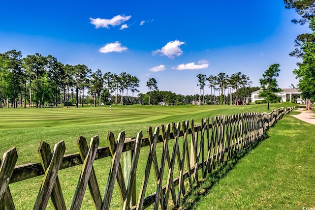 surrounding community with fence, a yard, and golf course view