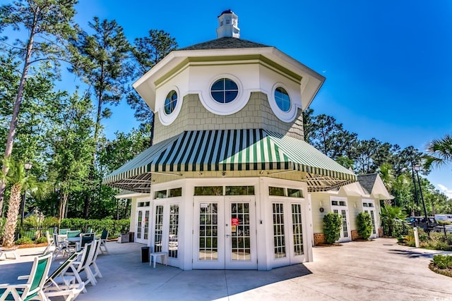 rear view of property featuring fence, a standing seam roof, french doors, a patio, and metal roof