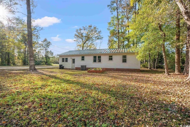 back of house featuring a standing seam roof, a yard, central AC, and metal roof