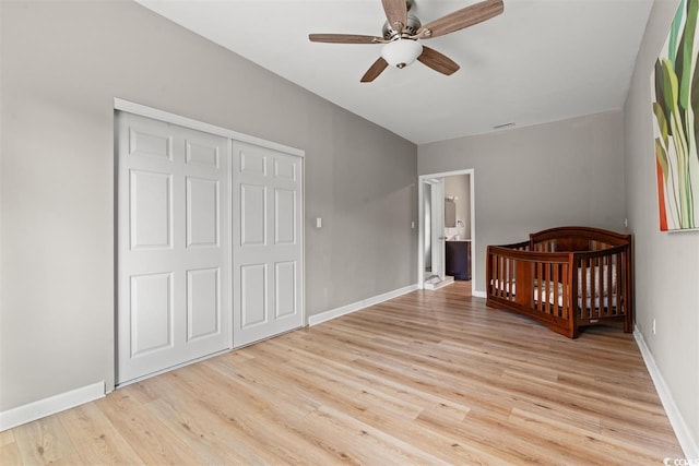 unfurnished bedroom featuring ceiling fan, light wood-style flooring, baseboards, visible vents, and a closet