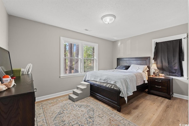 bedroom featuring baseboards, visible vents, and light wood-type flooring