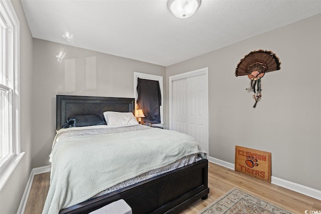 bedroom featuring baseboards, a closet, and light wood finished floors