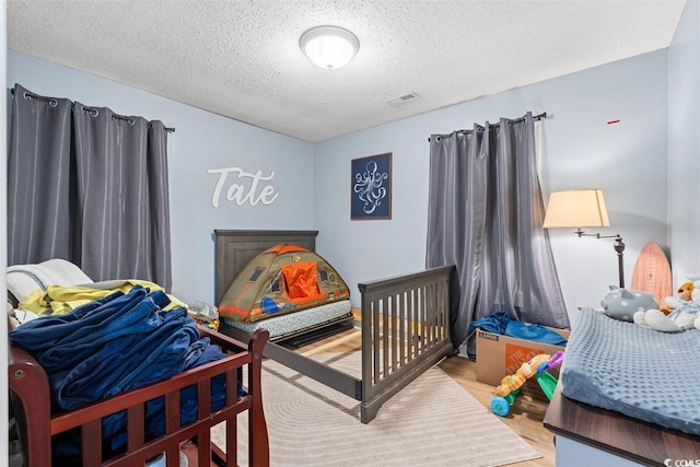 bedroom featuring visible vents, a textured ceiling, and wood finished floors