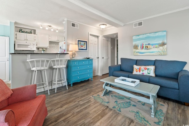 living area with visible vents, crown molding, and dark wood-style floors