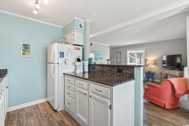 kitchen featuring crown molding, freestanding refrigerator, a peninsula, white cabinetry, and wood finished floors